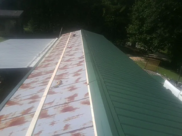 Old rusted panels beside newly installed green metal roofing — Wind Damage Roof Repair by Roofing Brothers in Rock Springs