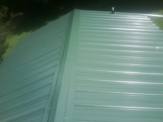 New green metal panels meeting at the ridge of a roof — Flat Roof Repair work by our crew in Rock Springs