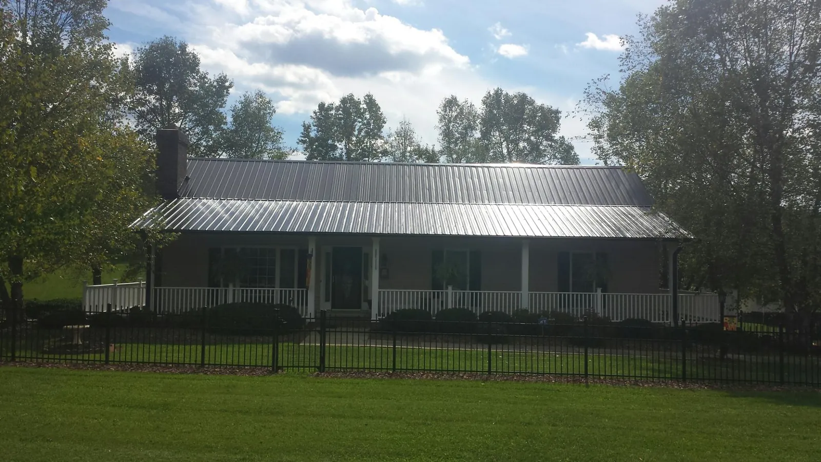 Gray metal roof on a brick ranch with a full width front porch — Gutter Guard Installation work by our crew in Rock Springs