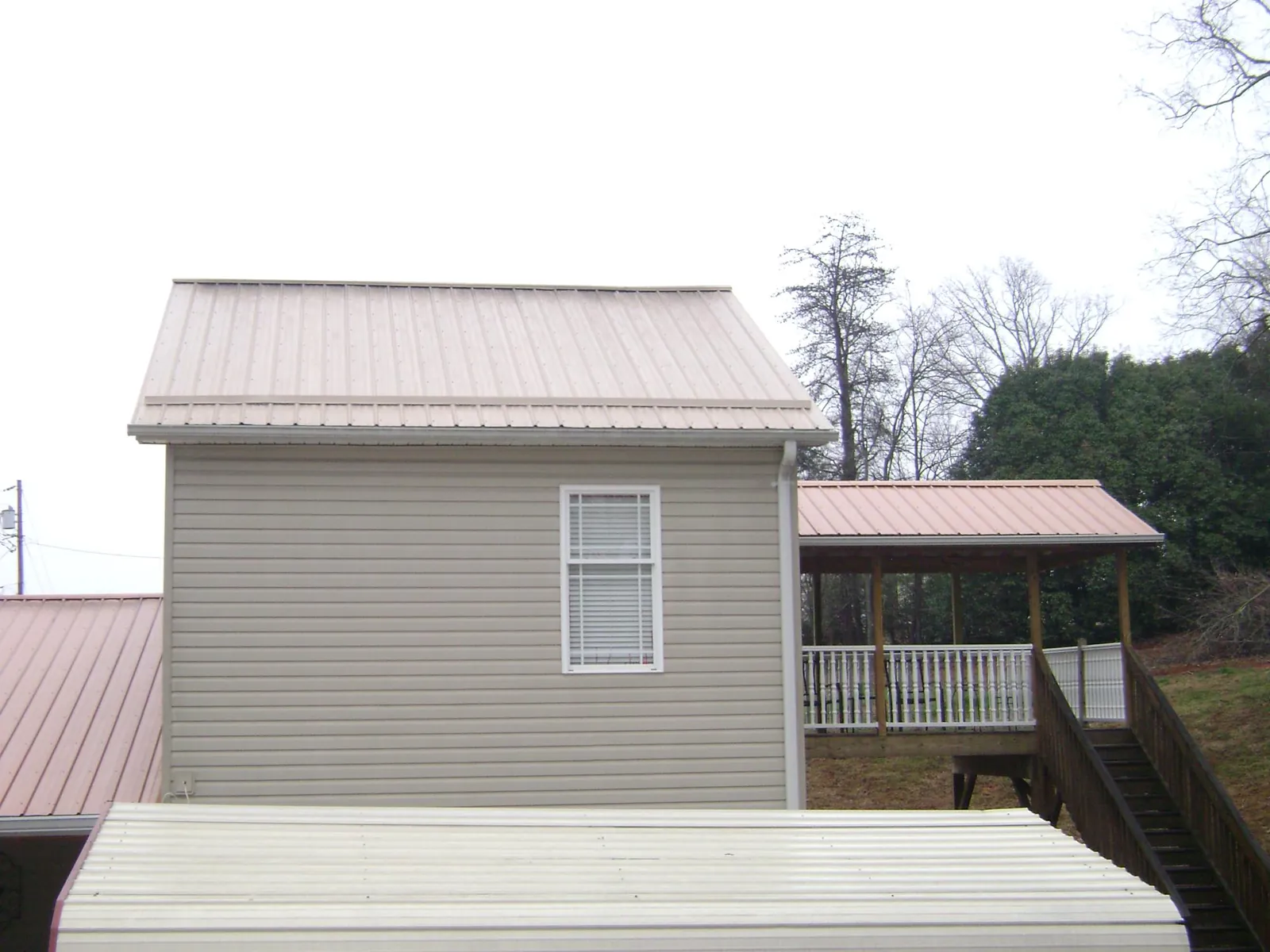 Tan metal roofs on a two story addition and attached porch, from a Roof Replacement job in Rock Springs