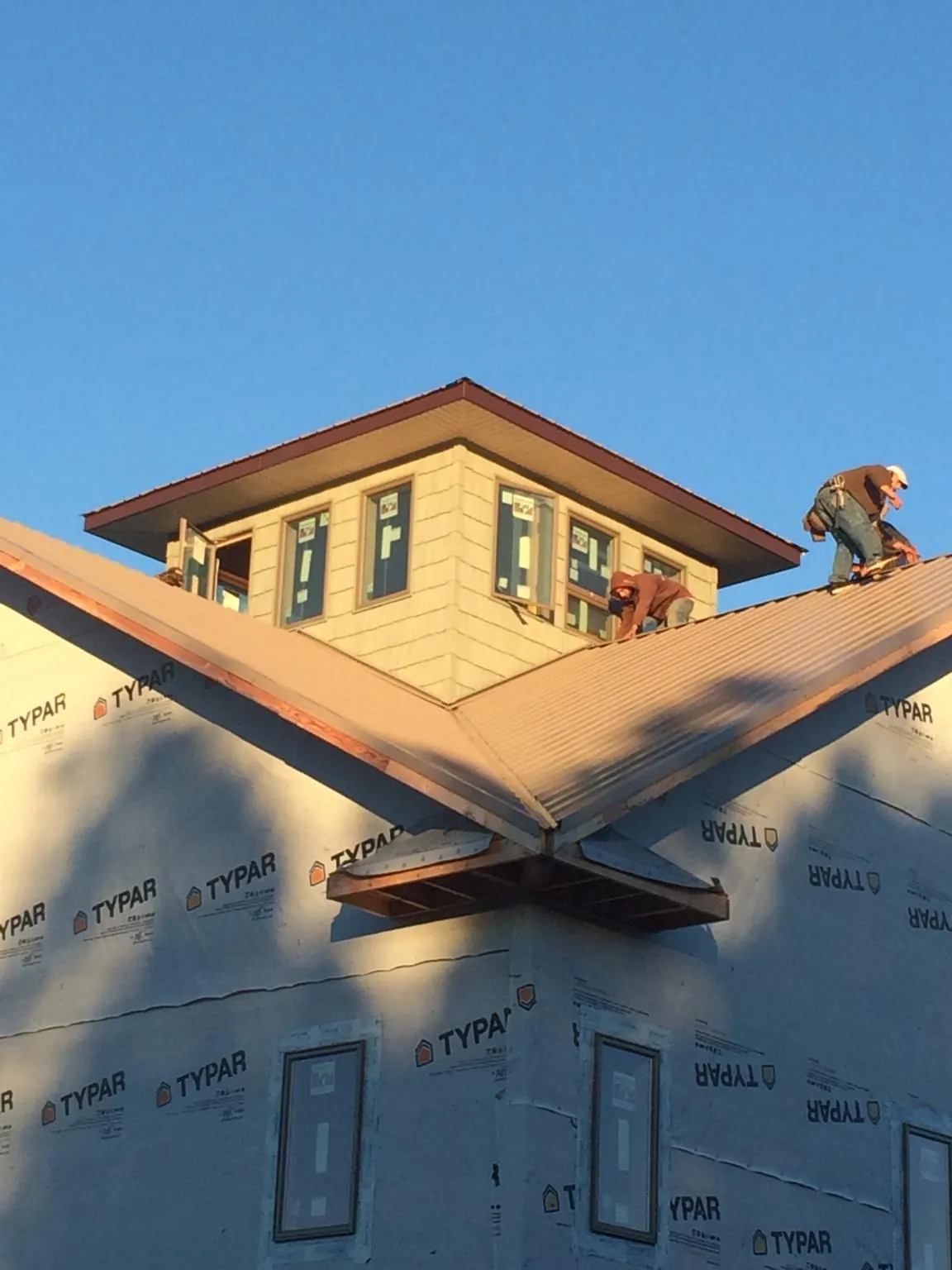 Roofers working around a rooftop cupola on a new metal roof at sunset — Roof Waterproofing in Rock Springs by Roofing Brothers